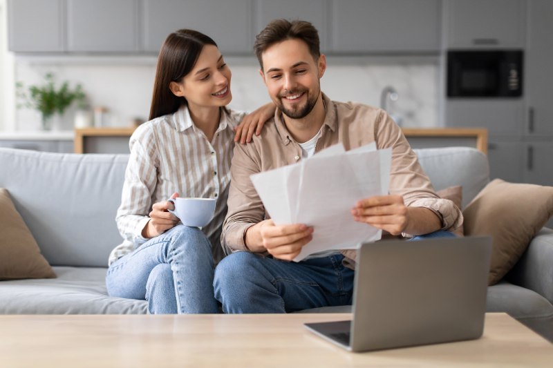 smiling-european-couple-with-coffee-documents-near-laptop