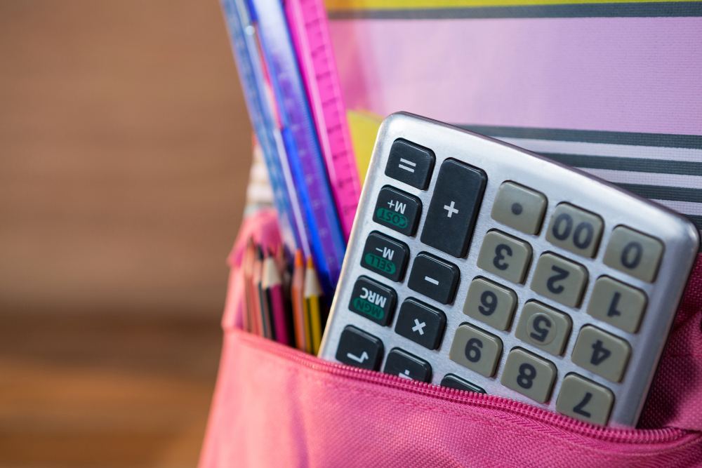 Calculator and school supplies inside a pink pencil case on a desk