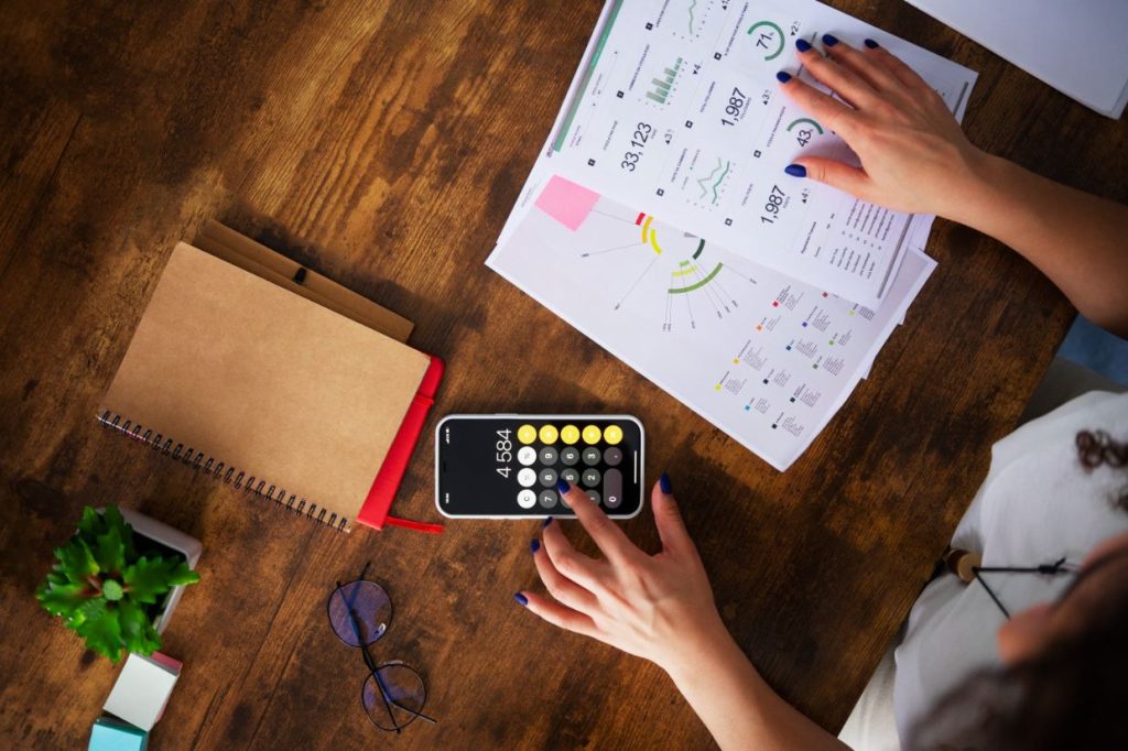 Woman analyzing financial data with a calculator and reports on a desk
